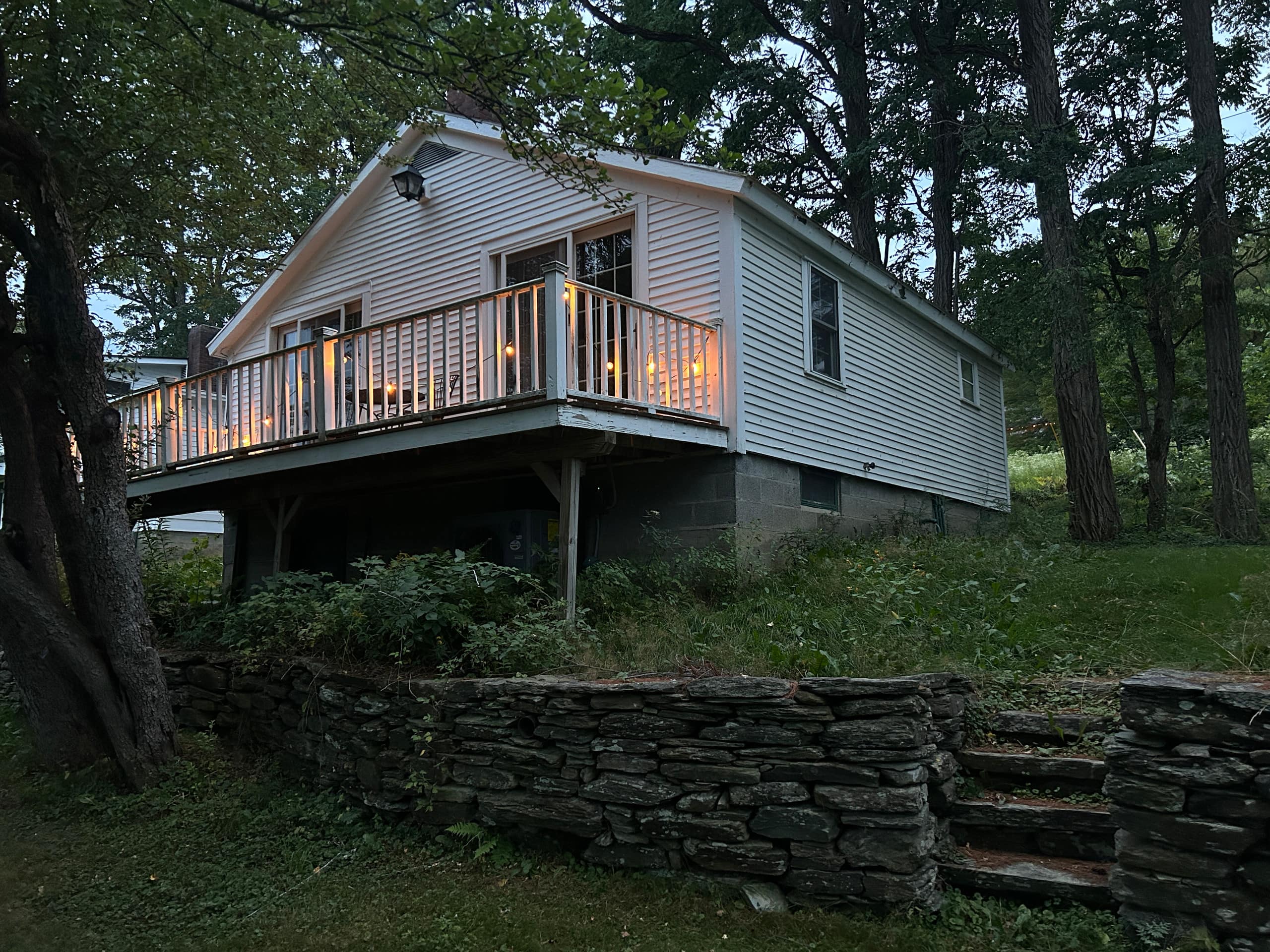 Earhart Cottage exterior at dusk with lit deck under tall trees